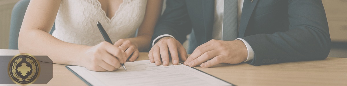 um casal lado a lado em um cartório, assinando um documento de casamento sobre a mesa
