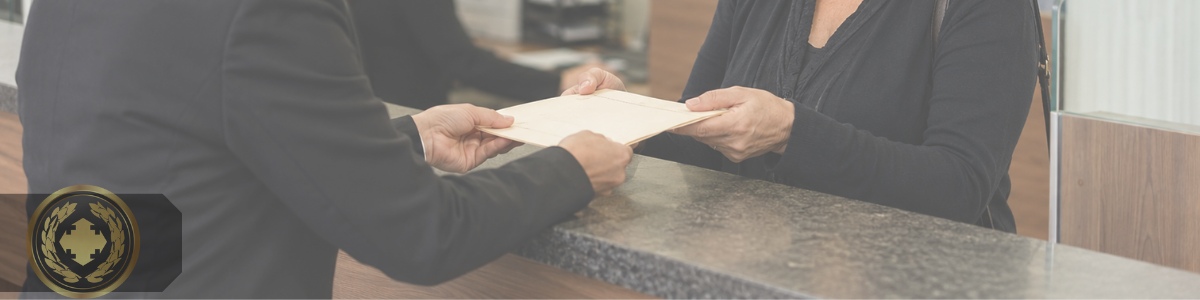 Uma mulher viúva recebe uma certidão em um cartório, em um atendimento discreto e acolhedor, com expressão séria e emotiva. A cena transmite confiança, formalidade e sensibilidade